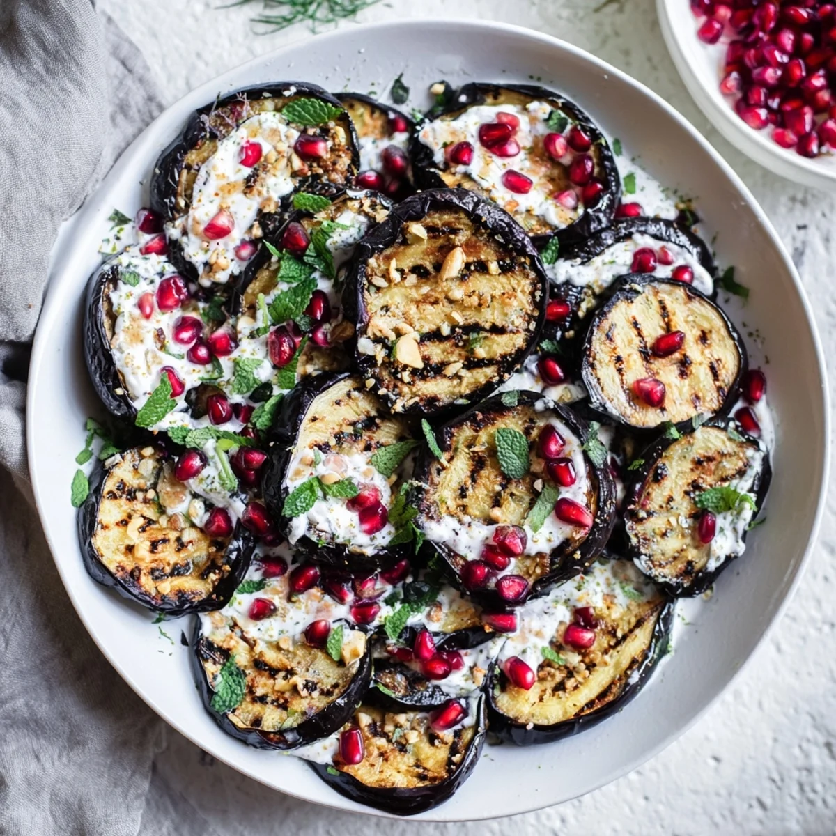 Roasted eggplant with a vibrant pomegranate, mint, and creamy yogurt sauce, perfect for a fresh meal.