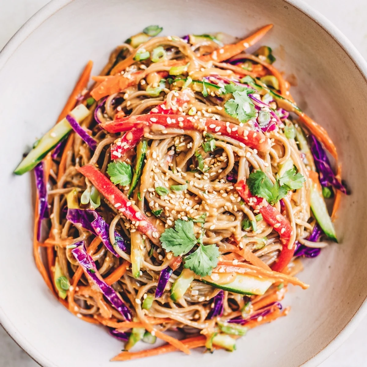 Vibrant soba noodle salad with colorful veggies, a creamy peanut dressing, and fresh herbs, ready to enjoy.