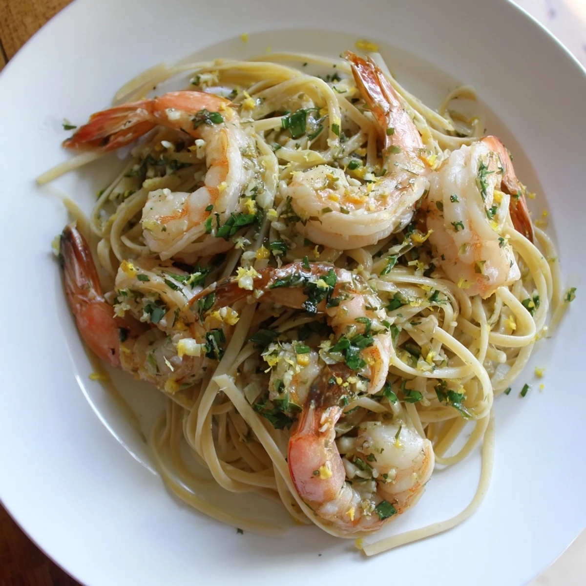 Steaming plate of Lemon Herb Pasta with Shrimp, vibrant and topped with fresh parsley and lemon wedges.