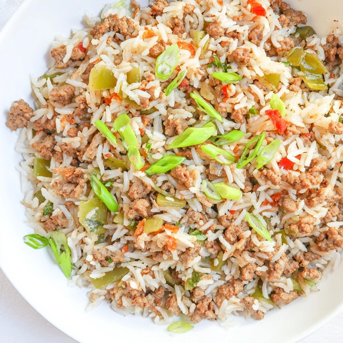 Steaming Cajun Dirty Rice, a hearty Southern meal, garnished with fresh green onions, ready to serve.