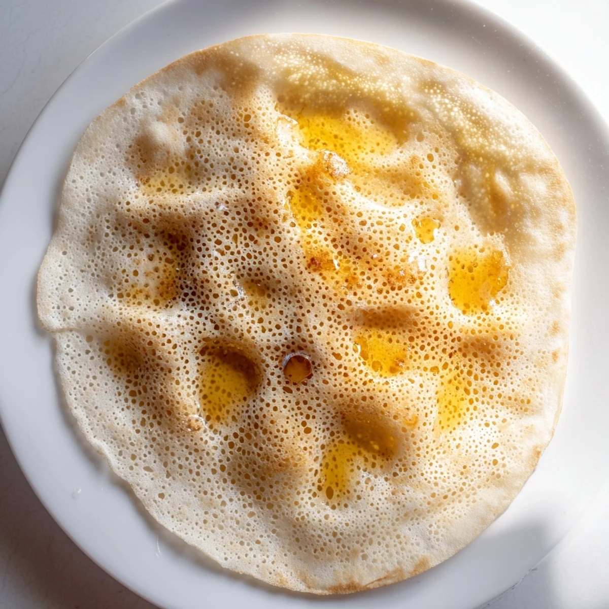 Golden, spongy Moroccan Baghrir crepes are bubbling and ready to be drizzled with flavorful honey.