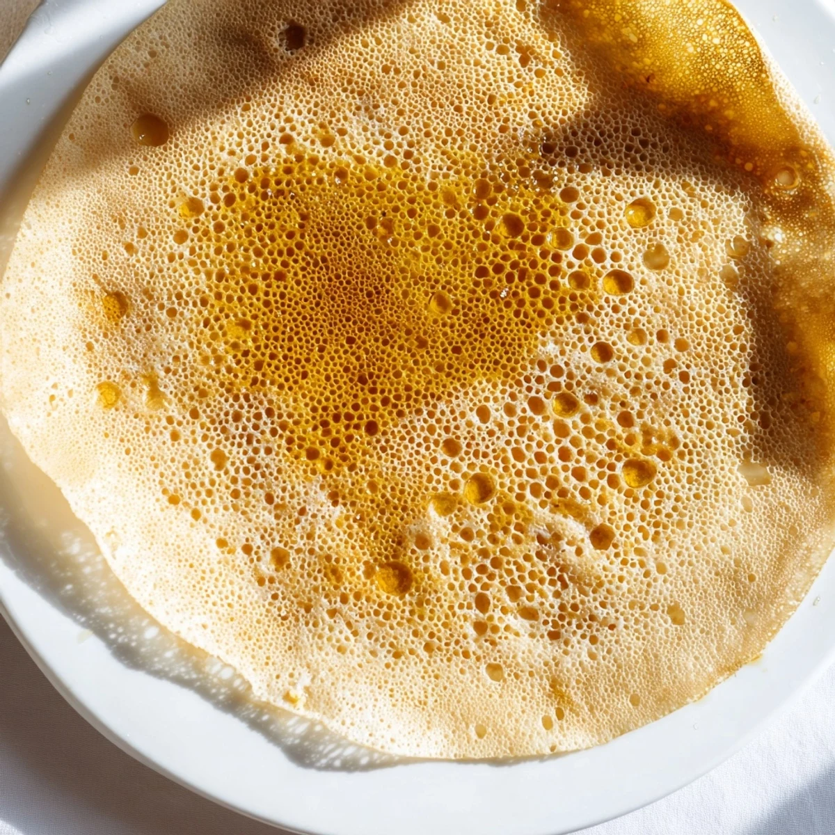 Perfectly cooked Moroccan Baghrir pancakes, showing off their delicate, airy holes and honeycomb texture.