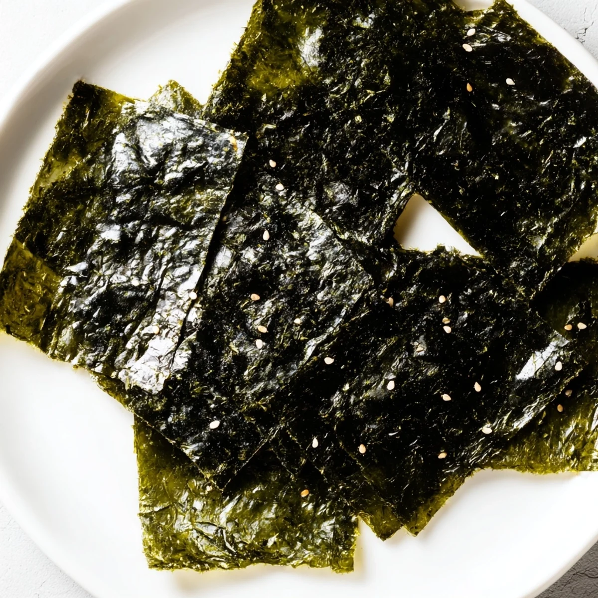 Vibrant, dark green roasted seaweed chips fanned out on a ceramic plate, steam rising slightly, ready to be enjoyed as a low-carb, gluten-free crunchy treat.