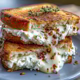 Crispy buttery grilled cheese halves revealing a melty chèvre and honey filling, served on a rustic wooden board.