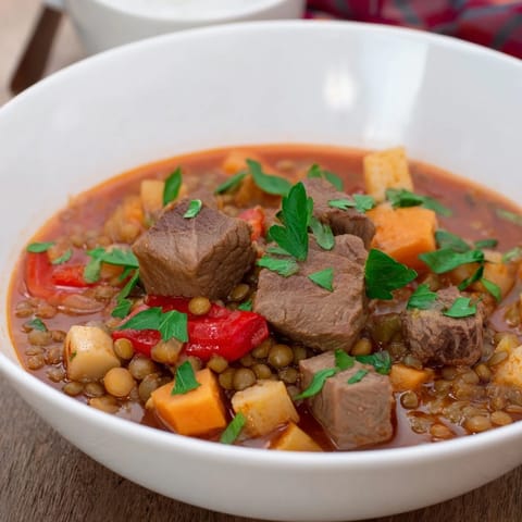 Close-up of a bubbling One-Pot Spicy Beef and Lentil Soup, full of beef and hearty lentils.