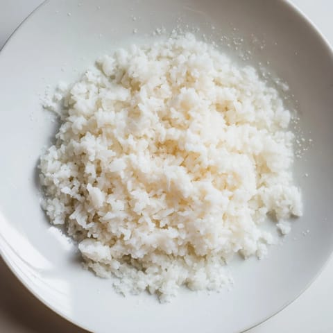 Steaming Coconut Jasmine Rice, showing glistening grains, with aromas of coconut and savory spices.