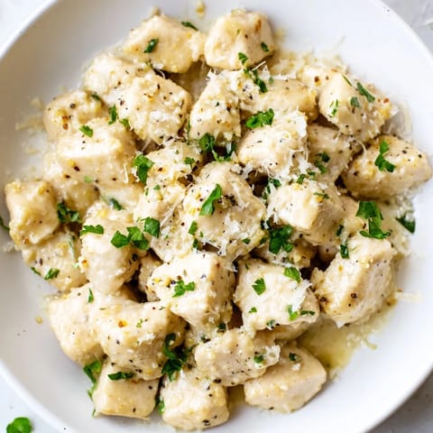 Tender chicken pieces coated in a velvety garlic cream sauce, served hot alongside steamed rice and a squeeze of lemon.