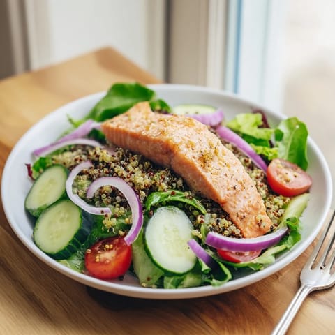 Lemon Herb Salmon Salad plated with warm salmon fillet over mixed greens, cherry tomatoes, cucumber, and fresh herbs for a bright, nourishing meal.  