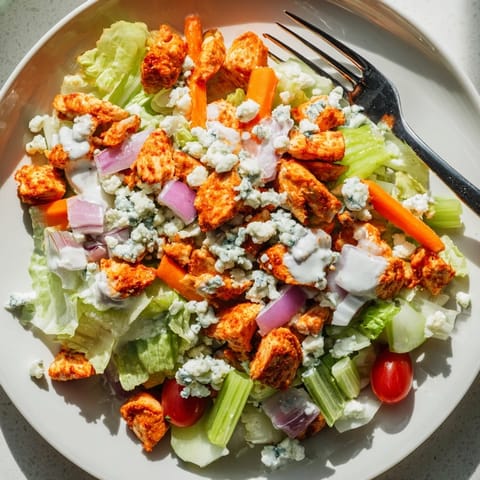 Juicy buffalo chicken pieces tossed with fresh chopped romaine, diced celery, and creamy blue cheese in a rustic bowl.
