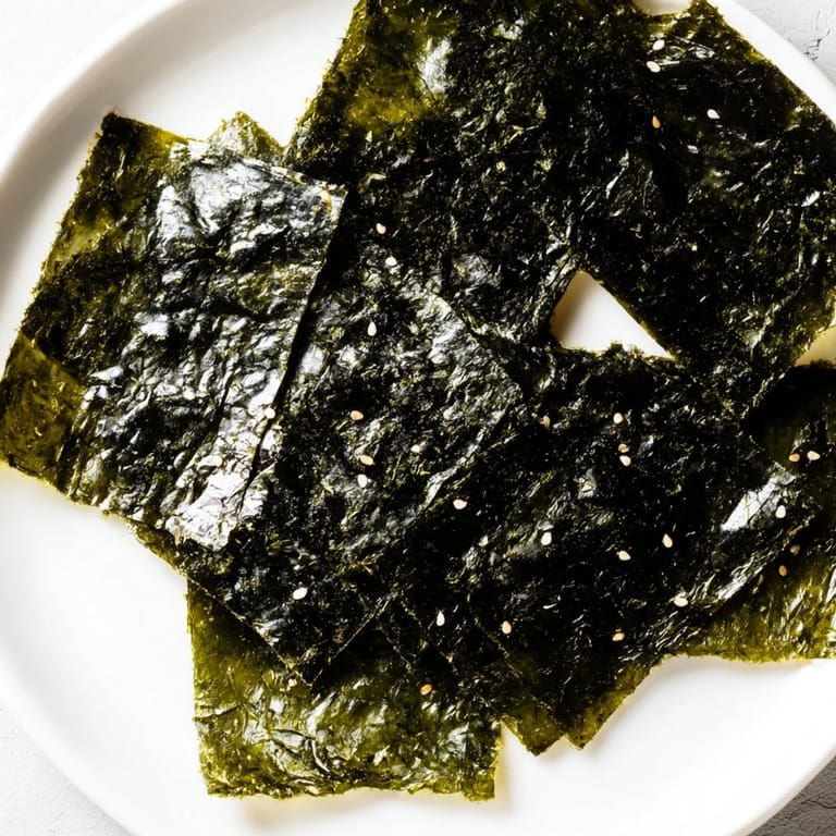 Vibrant, dark green roasted seaweed chips fanned out on a ceramic plate, steam rising slightly, ready to be enjoyed as a low-carb, gluten-free crunchy treat.